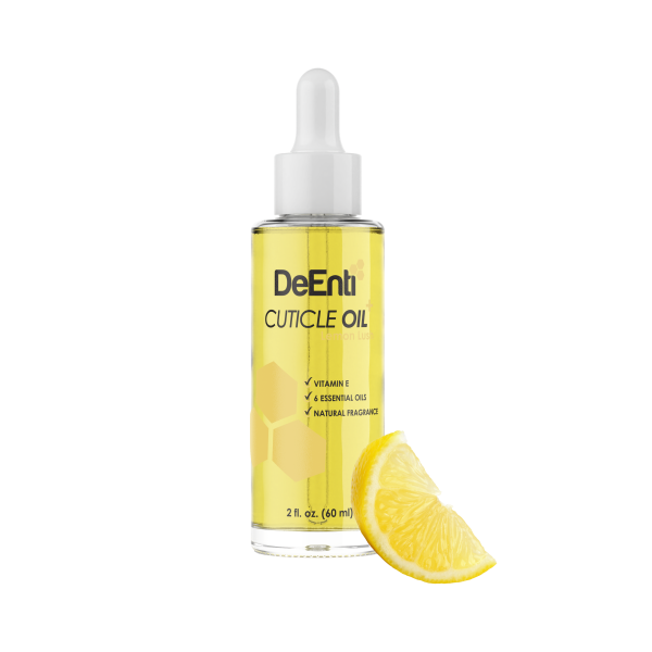 A 2 fl oz glass dropper bottle of DeEnti Lemon Lush Cuticle Oil resting next to a fresh, bright lemon wedge on a white background.